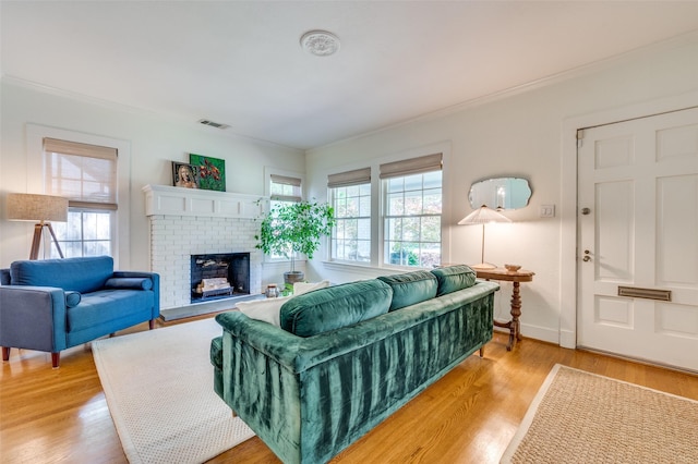 living area featuring visible vents, ornamental molding, a brick fireplace, and plenty of natural light