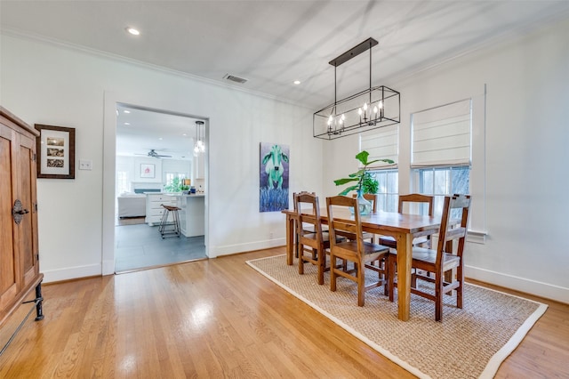 dining space featuring an inviting chandelier, ornamental molding, light wood-type flooring, and visible vents