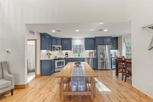 kitchen with a sink, appliances with stainless steel finishes, blue cabinets, and light countertops