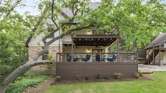 rear view of house with brick siding, ceiling fan, a deck, stairway, and a lawn