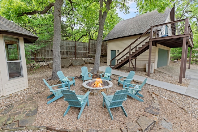 view of patio with a deck, a garage, stairway, fence, and an outdoor fire pit