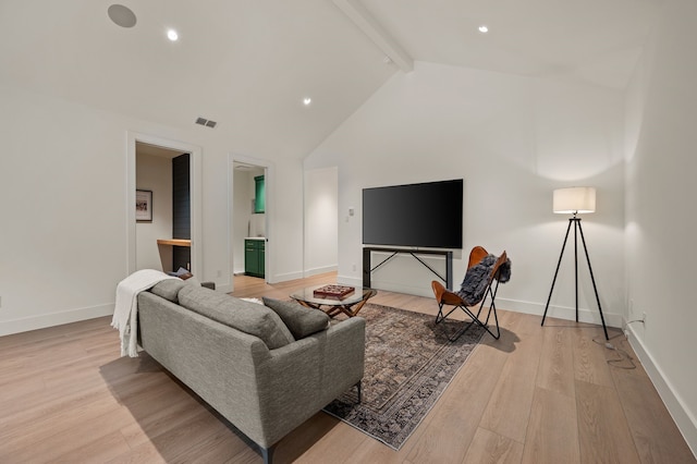 living area with baseboards, vaulted ceiling with beams, and light wood-style flooring