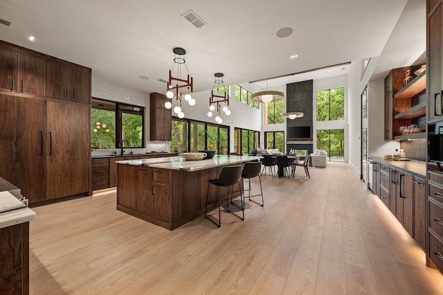 kitchen featuring visible vents, open shelves, open floor plan, a spacious island, and light wood-style flooring