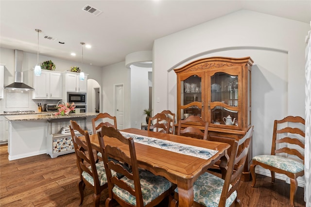 dining area with a toaster, arched walkways, light wood finished floors, and visible vents