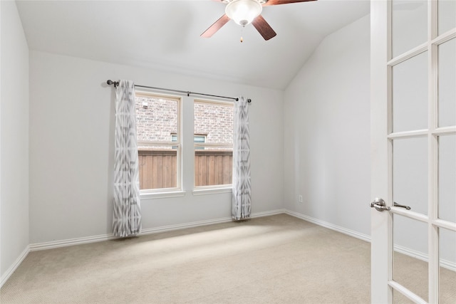 carpeted spare room featuring ceiling fan, vaulted ceiling, and baseboards