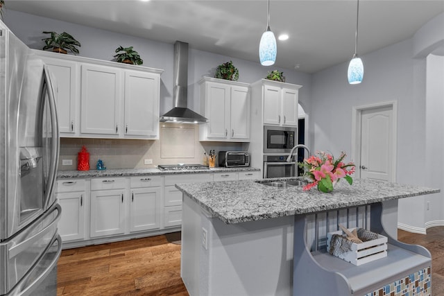 kitchen with white cabinets, stainless steel appliances, a sink, and wall chimney exhaust hood