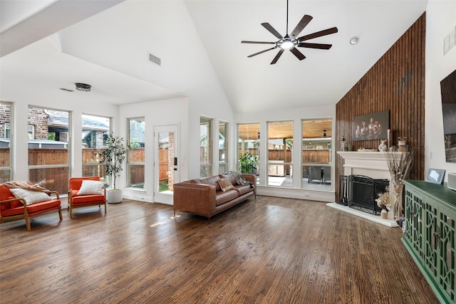 living room with ceiling fan, visible vents, wood finished floors, high vaulted ceiling, and a fireplace with raised hearth