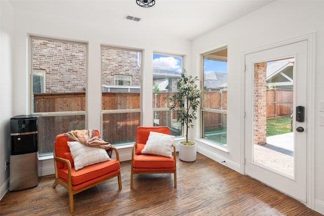sunroom with baseboards, visible vents, and wood finished floors