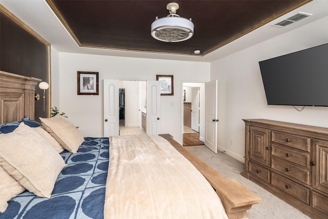 bedroom featuring visible vents, a raised ceiling, baseboards, and light carpet