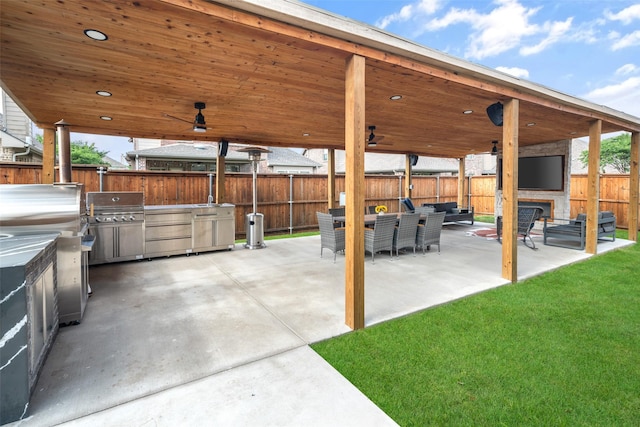 view of patio / terrace featuring grilling area, exterior kitchen, a fenced backyard, and an outdoor living space with a fireplace