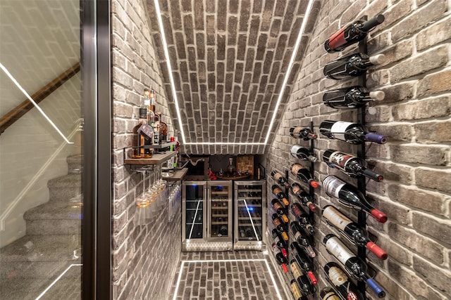 wine cellar featuring wine cooler and brick wall
