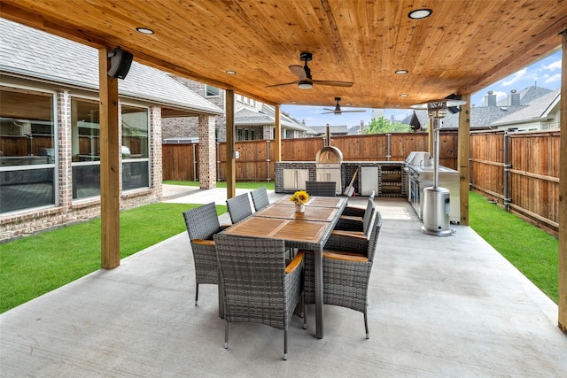 view of patio with an outdoor kitchen, a ceiling fan, outdoor dining area, and a fenced backyard