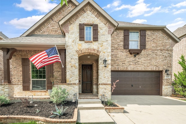 french provincial home with brick siding, an attached garage, driveway, and stone siding