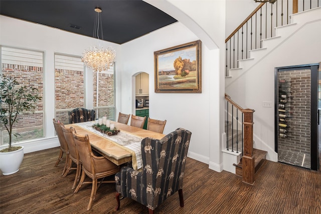 dining room with arched walkways, baseboards, wood finished floors, visible vents, and stairway