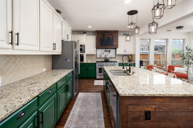 kitchen with a sink, appliances with stainless steel finishes, white cabinets, and a center island with sink