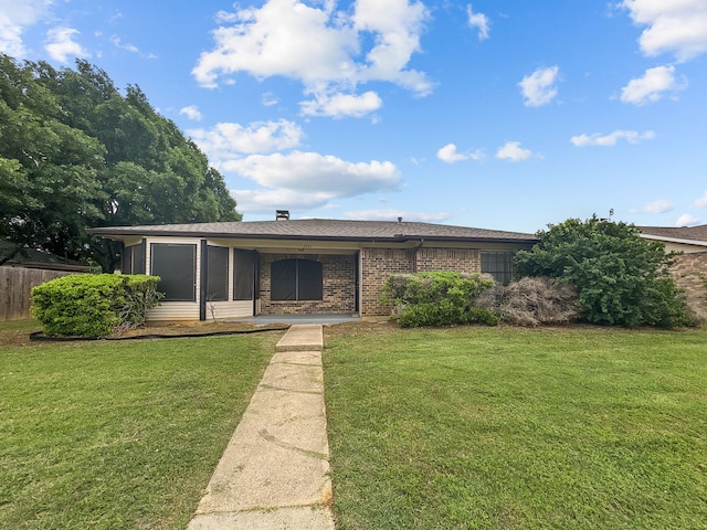 view of front of home featuring brick siding, fence, a front yard, and roof with shingles