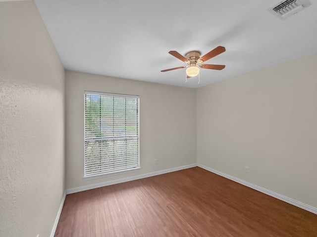 spare room featuring visible vents, a ceiling fan, baseboards, and wood finished floors