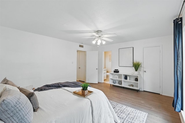 bedroom featuring visible vents, a ceiling fan, connected bathroom, and wood finished floors