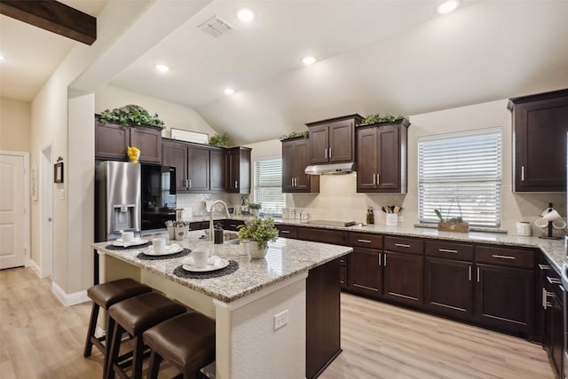 kitchen with visible vents, lofted ceiling, dark brown cabinetry, light wood finished floors, and backsplash