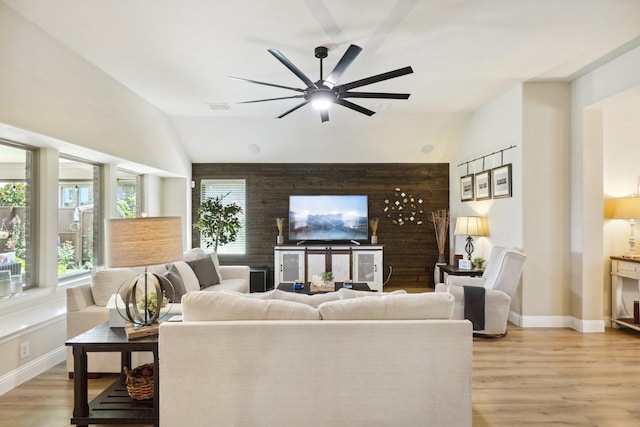 living room with baseboards, a ceiling fan, lofted ceiling, and light wood-type flooring