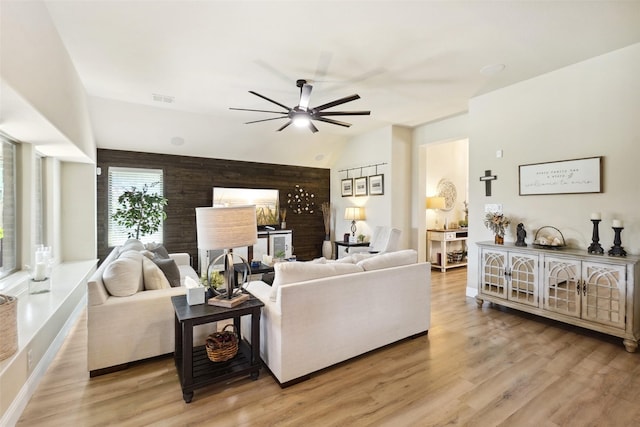 living area featuring ceiling fan, visible vents, lofted ceiling, and light wood-type flooring