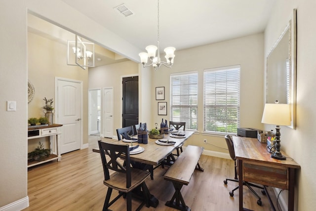 dining space with an inviting chandelier, baseboards, light wood finished floors, and visible vents