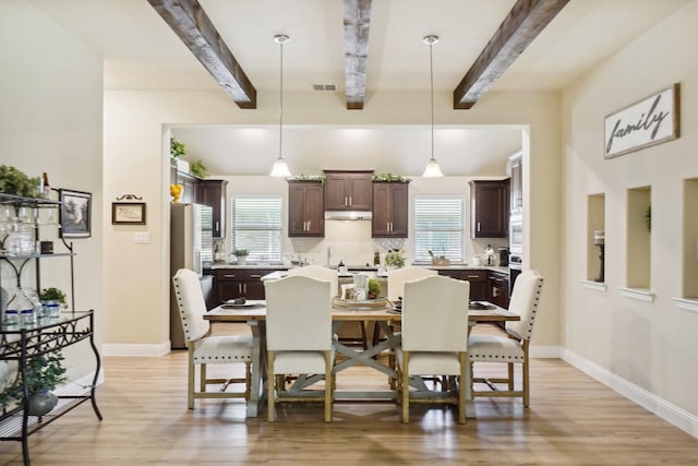 dining room featuring baseboards, light wood-style flooring, and beamed ceiling