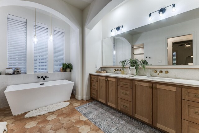 full bath featuring double vanity, a freestanding tub, and a sink