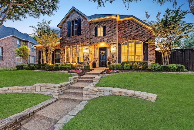 view of front of property featuring brick siding, fence, and a front lawn