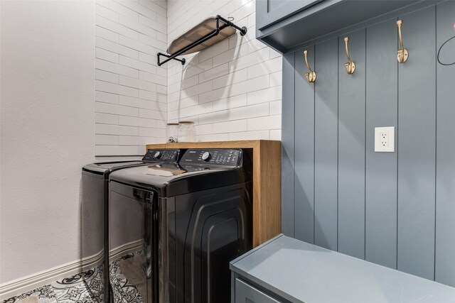washroom with cabinet space, baseboards, and washing machine and dryer