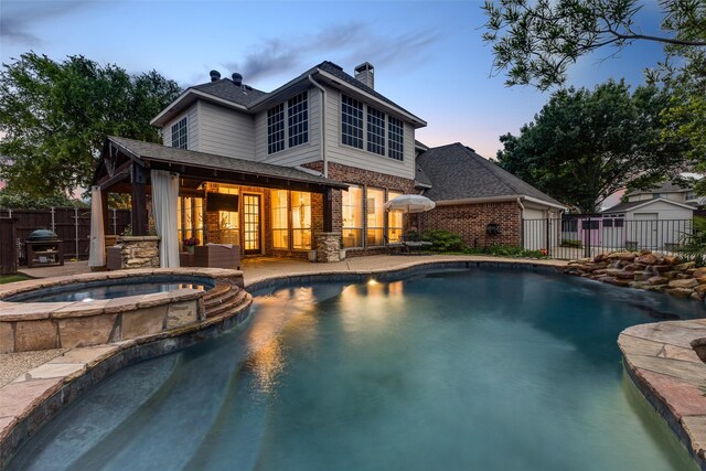 view of pool featuring a pool with connected hot tub, a shed, a fenced backyard, an outbuilding, and a patio