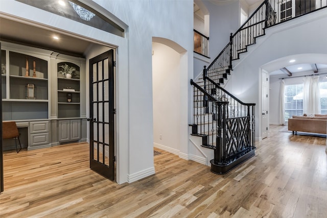 living room featuring a healthy amount of sunlight, beamed ceiling, a fireplace, and wood finished floors