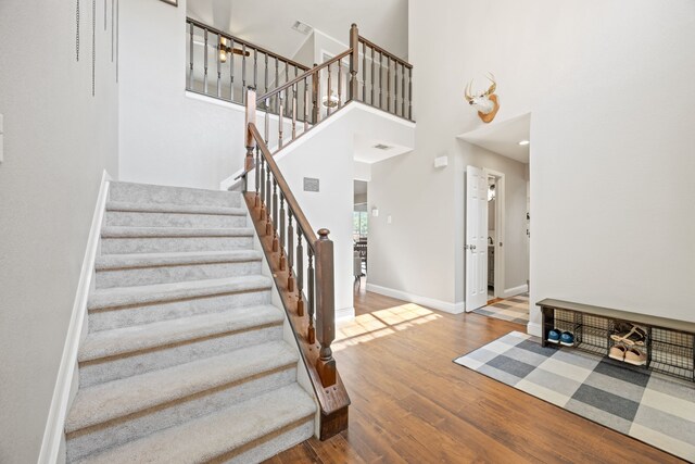 entrance foyer featuring stairs, baseboards, a high ceiling, and wood finished floors