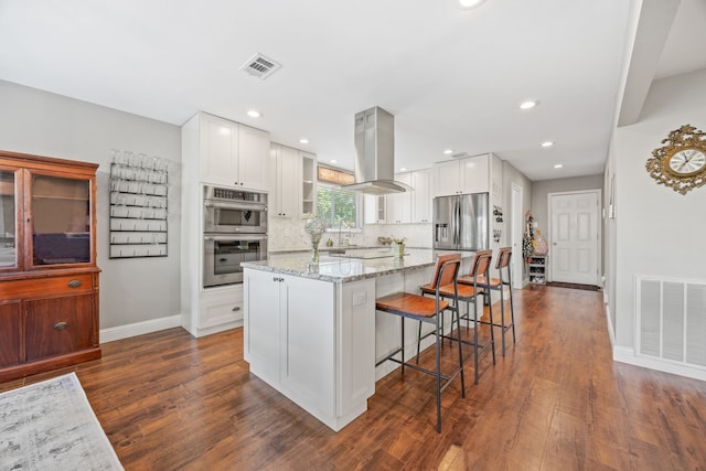 kitchen featuring dark wood-style flooring, stainless steel appliances, baseboards, a kitchen bar, and visible vents