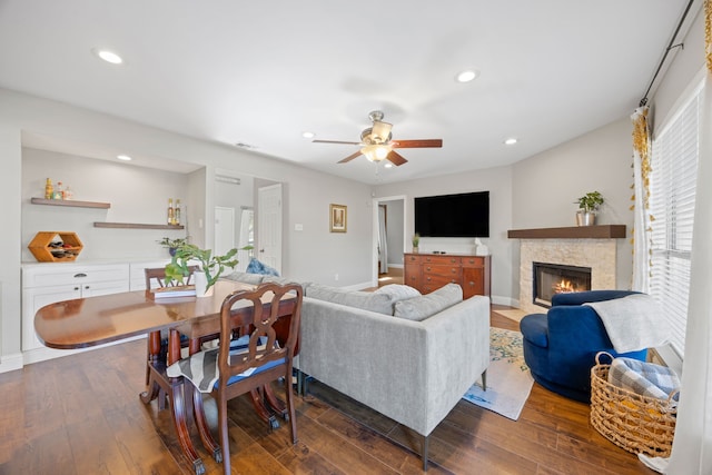living area with a fireplace, baseboards, ceiling fan, dark wood-type flooring, and recessed lighting