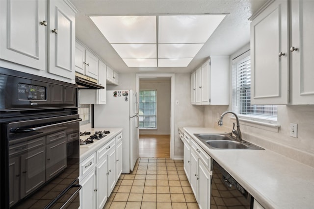 kitchen featuring light countertops, white cabinets, a sink, and black appliances