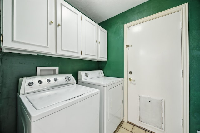 laundry area featuring washing machine and clothes dryer, light tile patterned floors, and cabinet space