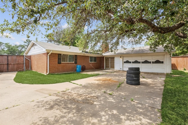 single story home featuring brick siding, a front lawn, fence, and driveway
