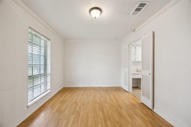 unfurnished bedroom featuring visible vents, light wood-style flooring, crown molding, and baseboards
