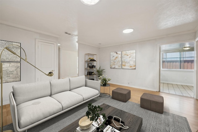 living area featuring crown molding, baseboards, visible vents, and wood finished floors