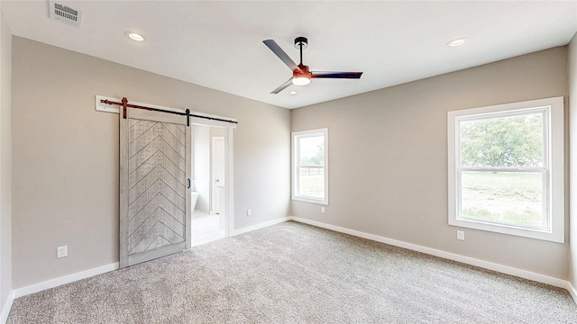 unfurnished bedroom with visible vents, a barn door, baseboards, carpet, and recessed lighting