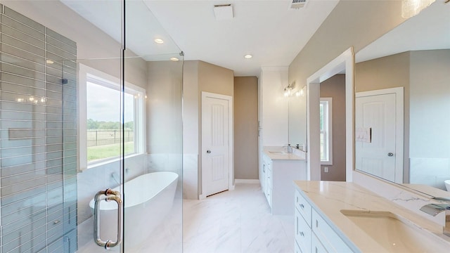 bathroom with a sink, a freestanding bath, marble finish floor, and two vanities