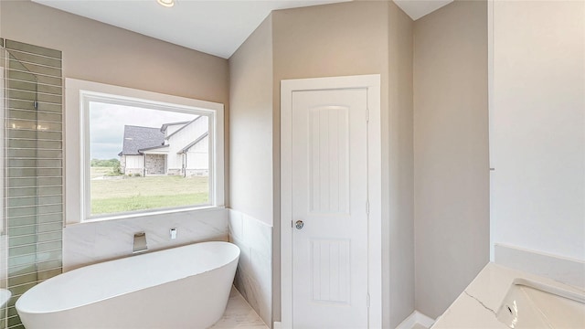 bathroom with tile walls and a soaking tub