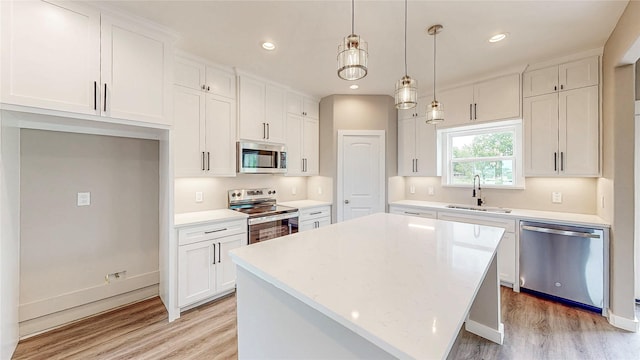 kitchen featuring a sink, stainless steel appliances, light wood-type flooring, and white cabinetry