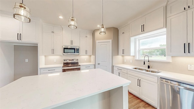 kitchen featuring decorative light fixtures, a sink, white cabinets, stainless steel appliances, and recessed lighting