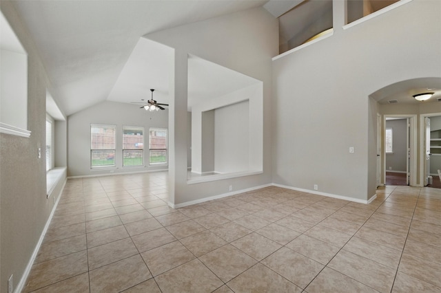 unfurnished living room with baseboards, a ceiling fan, arched walkways, and light tile patterned floors