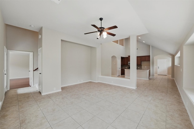 unfurnished living room featuring ceiling fan, arched walkways, baseboards, light tile patterned floors, and vaulted ceiling