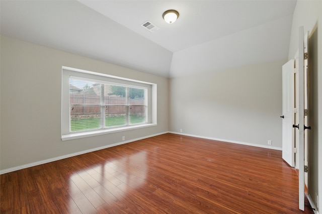unfurnished room featuring baseboards, vaulted ceiling, wood finished floors, and visible vents