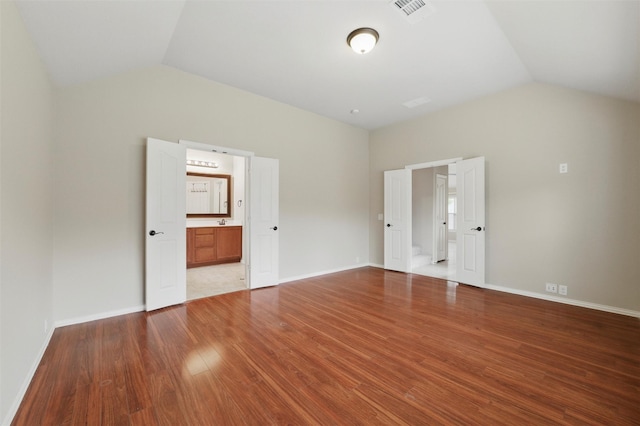 interior space with visible vents, baseboards, wood finished floors, and vaulted ceiling