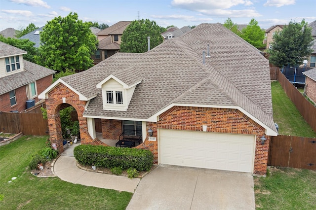 traditional home with a front yard, a fenced backyard, brick siding, a shingled roof, and concrete driveway